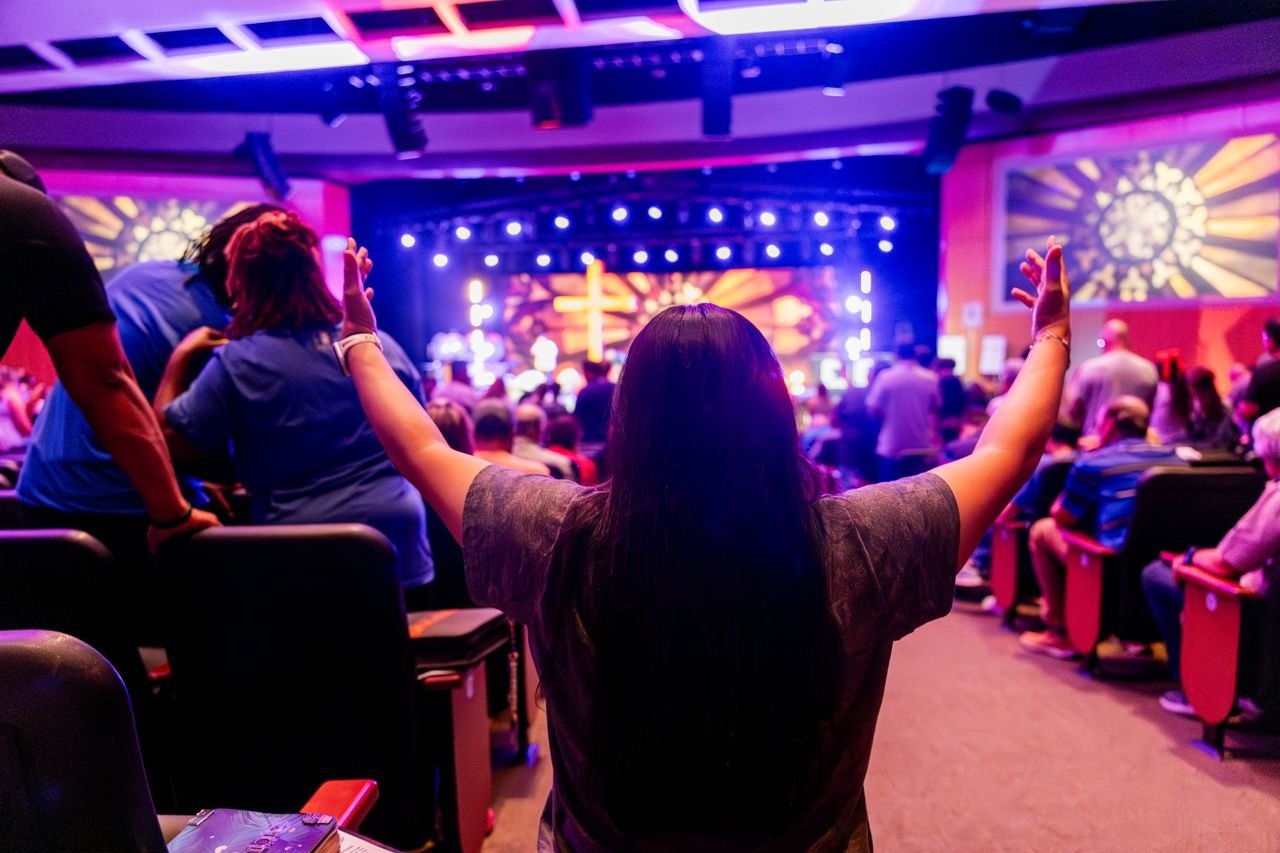 An energetic church congregation with raised hands during a worship service in a vibrant setting.